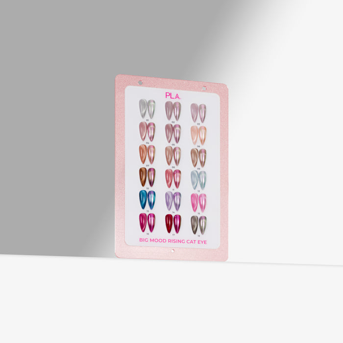 A pink display Nail Swatch card showing multiple shades of cat-eye nail polish, labeled 'PLA' and 'BIG MOOD RISING CAT EYE,' photographed against a clean light gray background.