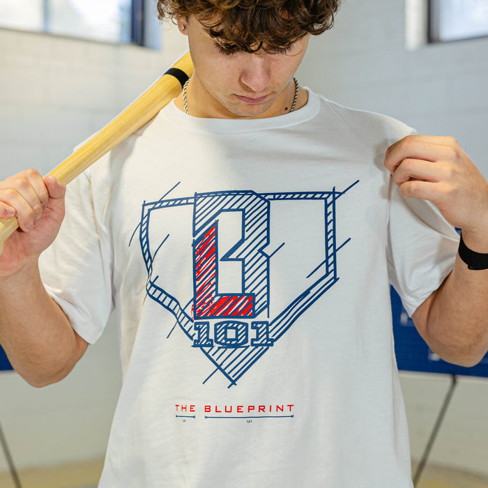 Person wearing a white t-shirt with a big BL101 logo and 'The Blueprint' text, holding a baseball bat