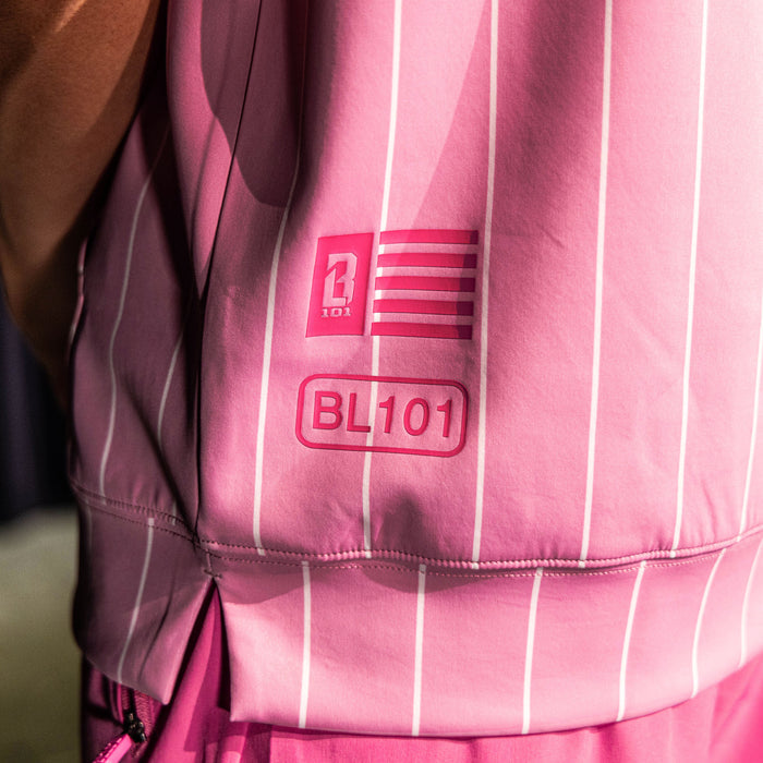 Close-up of the side hem detail on the pink pinstripe BSBL-SZN Short Sleeve Hoodie V3 showing the BL101 flag badge and "BL101" label graphic