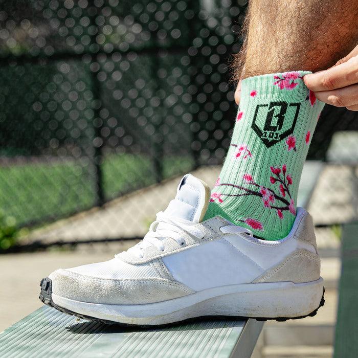 Adult model wearing multi-color socks with "Cherry Blossoms Performance 3-Pack" design
