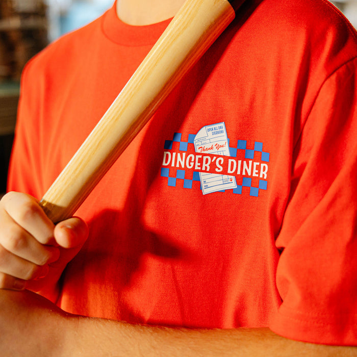 Person wearing a red shirt with 'Dinger's Diner' logo holding a wooden bat.