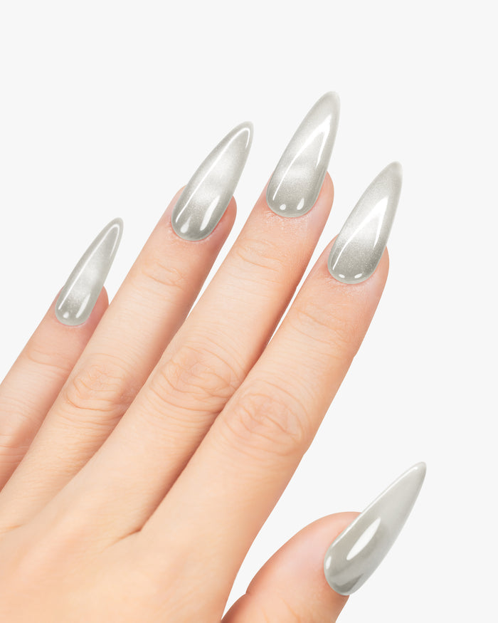 Hand with stiletto nails painted in a metallic silver color on a white background