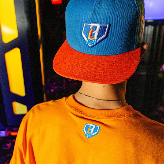 Person wearing a blue and red BL101 cap , standing in front of colorful lights.