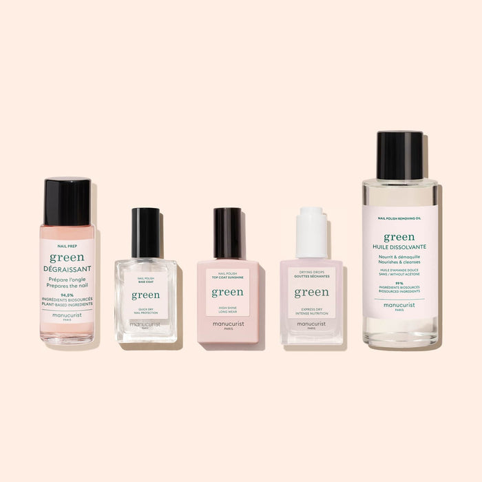 Five bottles of Manucurist nail care, featuring Green Base Coat, nail prep, nail oil, nail serum, and polish remover, lined up on a beige background—ideal for longer-lasting polish wear.