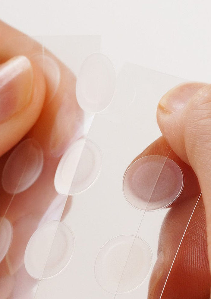 Close-up of a hand holding a contact lens with a blurred background
