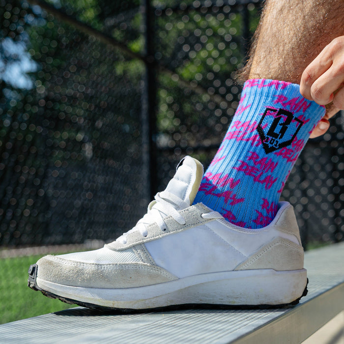 Adult model wearing multi-color socks with "Rain Delay Performance 3-Pack" design