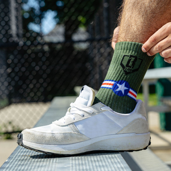 Adult model wearing green socks with "Warhawk Performance 3-Pack" design