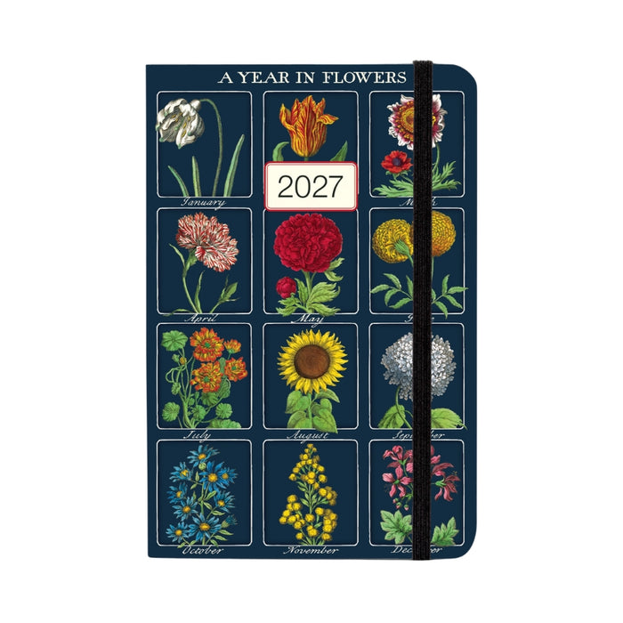A vertical 2027 floral planner or desk calendar with a dark navy cover printed with twelve vintage-style flower illustrations for each month, plus a black elastic closure band.