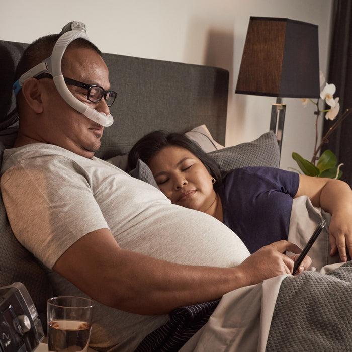 Man reading in bed while wearing an Airlift P30i Nasal cpap mask