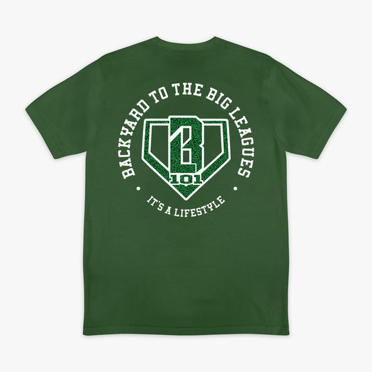 Image 1: Back flat lay of the BL101 Backyard to the Big Leagues forest green tee, featuring a circular "It's a Lifestyle" graphic with a grass-textured BL101 logo on a white background.