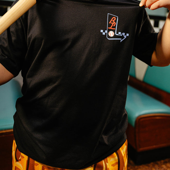Person wearing a black t-shirt with a BL101 logo, standing on a wooden stool.