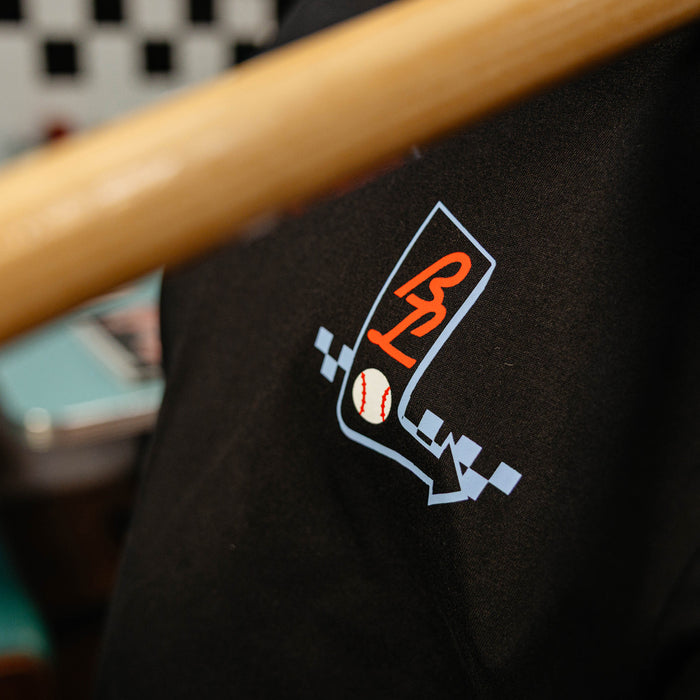 Close up of black shirt with a BL101 logo featuring a baseball on a blurred background