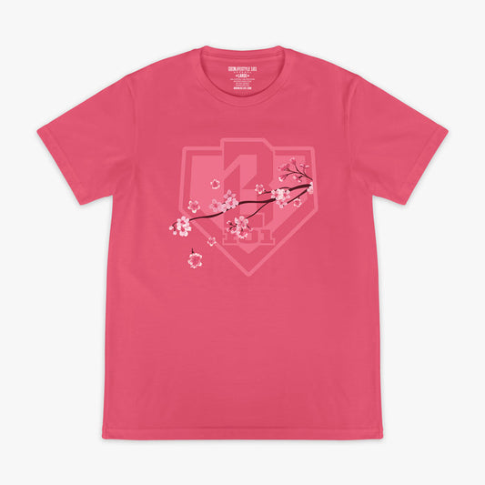 Pink BL101 tee with a tonal cherry blossom branch and home plate shield logo graphic on the chest, flat lay front view