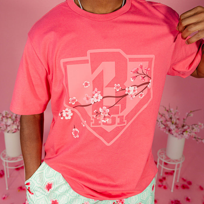 Close up of the tonal cherry blossom branch and home plate shield graphic on a pink BL101 tee worn by a male model