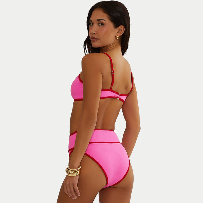 Woman wearing a pink bikini with red accents on a white background