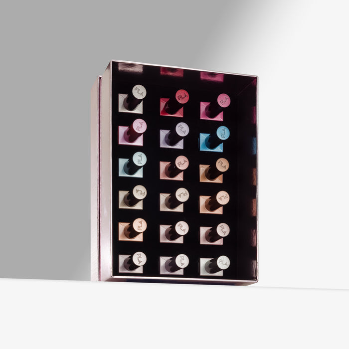 A rectangular black display box holding 18 nail polish bottles arranged in a grid, photographed on a clean light gray studio background.