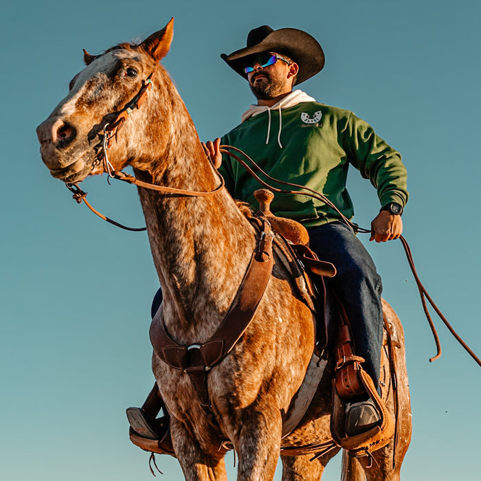Man riding a horse in a green BL101 Rodeo Club hoodie