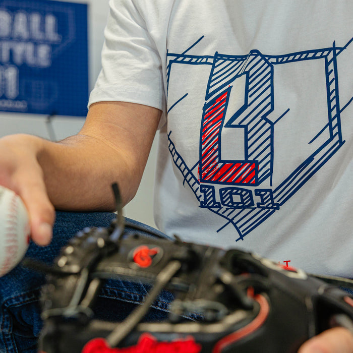 Person wearing a white t-shirt with a blue and red BL101 graphic, holding a baseball and glove.
