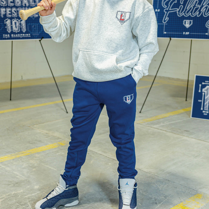 Person wearing a gray hoodie and blue pants with BL101 logos, standing in an indoor setting.