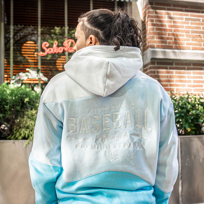 Person wearing light blue and white hoodie with 'Authentic Baseball Lifestyle PREMIUM APPAREL' text outdoors