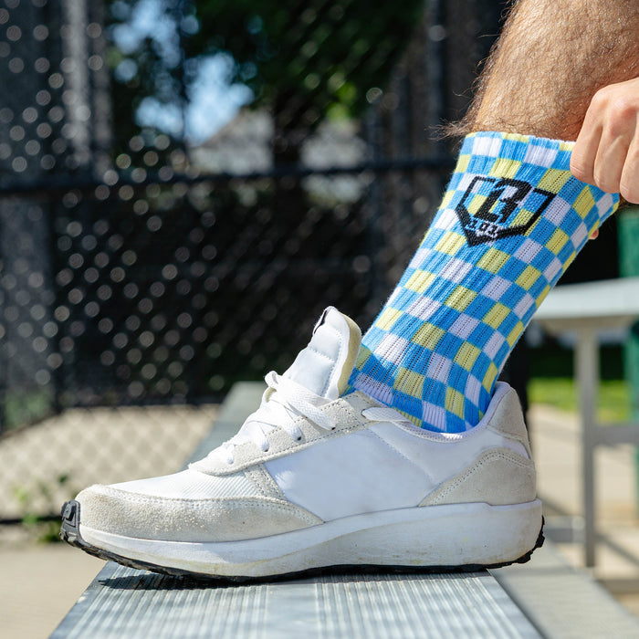 Adult model wearing multi-color socks with "Checker Print Performance  3-Pack" design