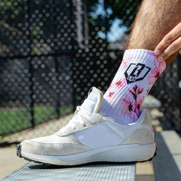 Adult model wearing multi-color socks with "Cherry Blossoms Performance  3-Pack" design