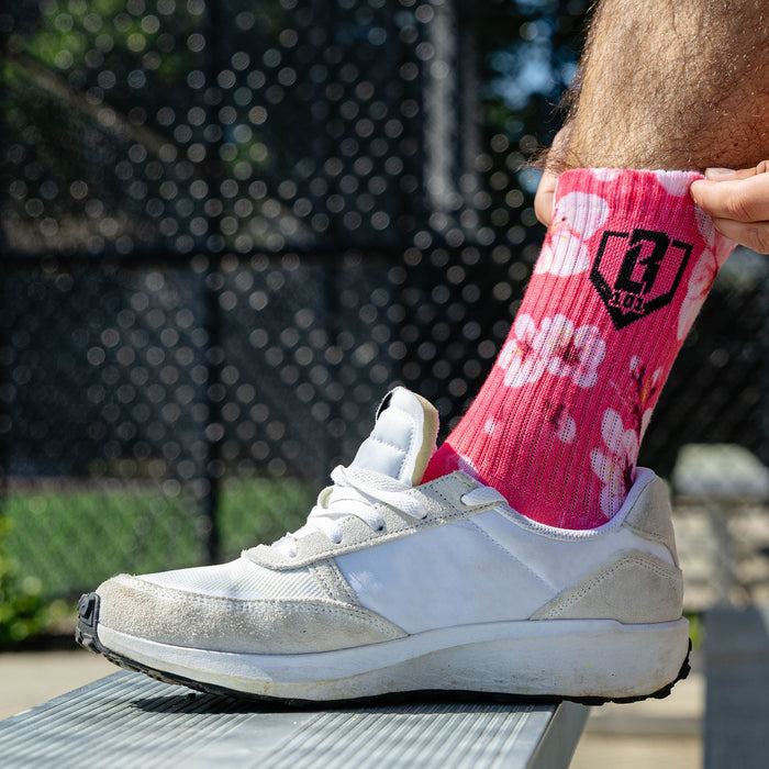 Adult model wearing multi-color socks with "Cherry Blossoms Performance  3-Pack" design