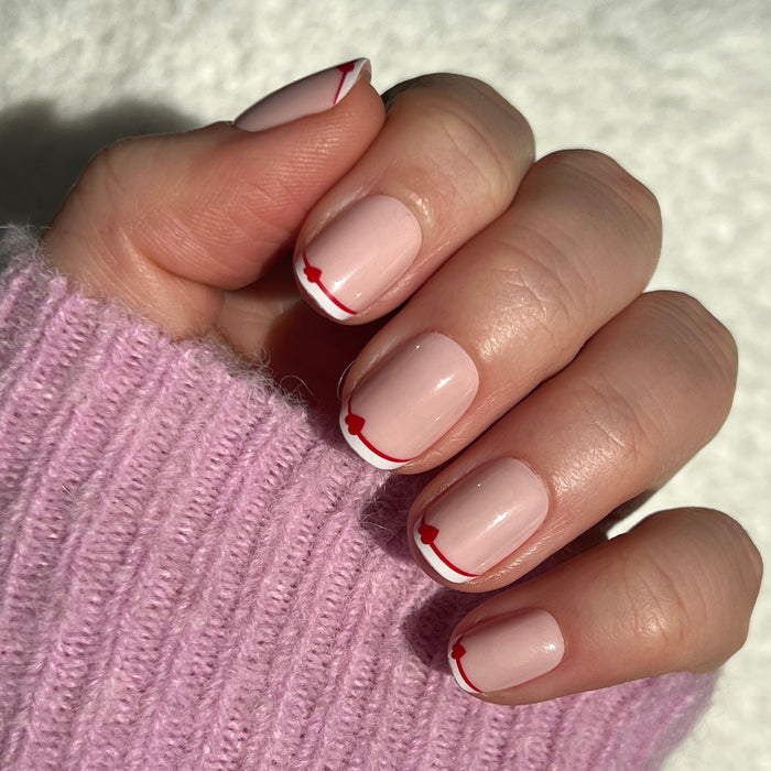 Classic French with CV Heart - Squoval | Extra Short press-on nails with peachy pink base, white tips, and red heart details on hand