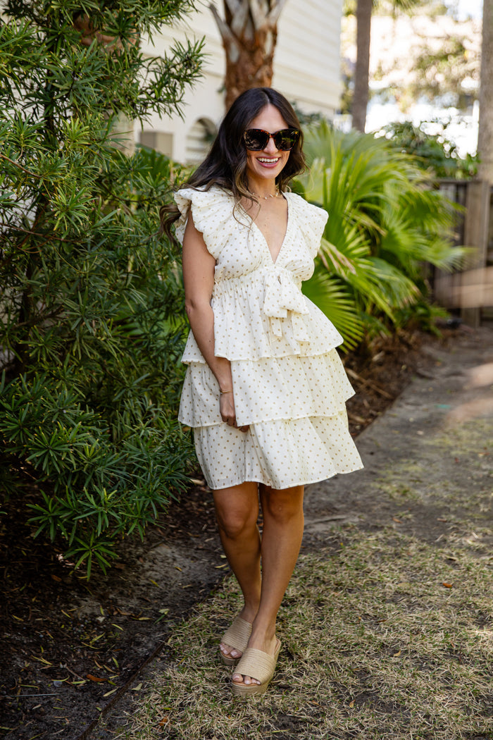 Woman in a white floral dress standing outdoors with greenery around