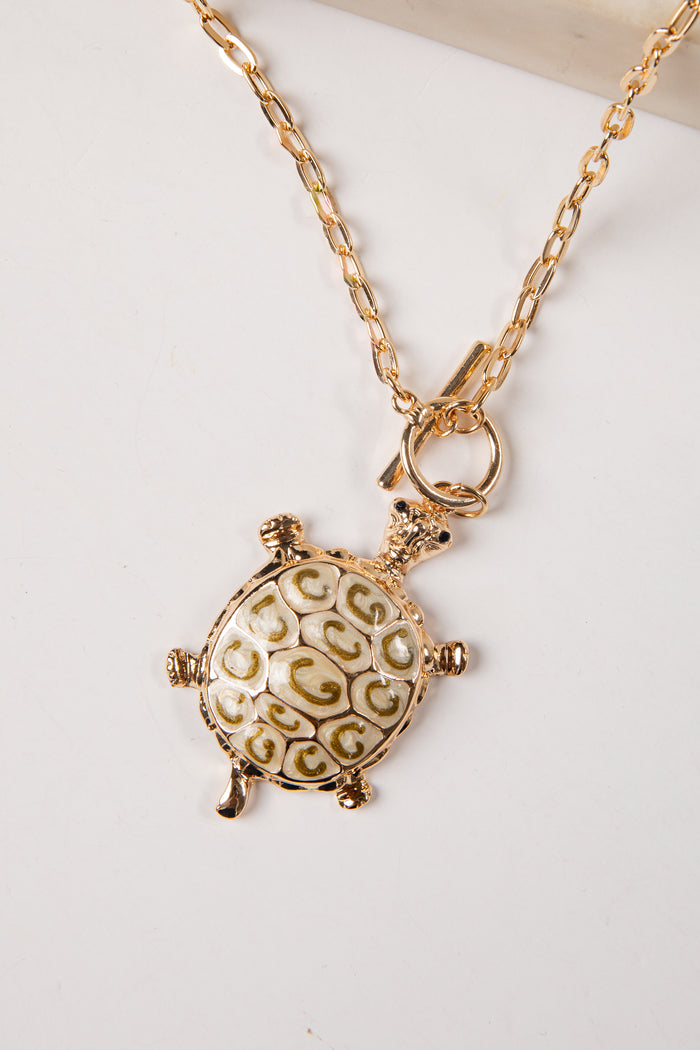 Gold turtle pendant necklace on a white background
