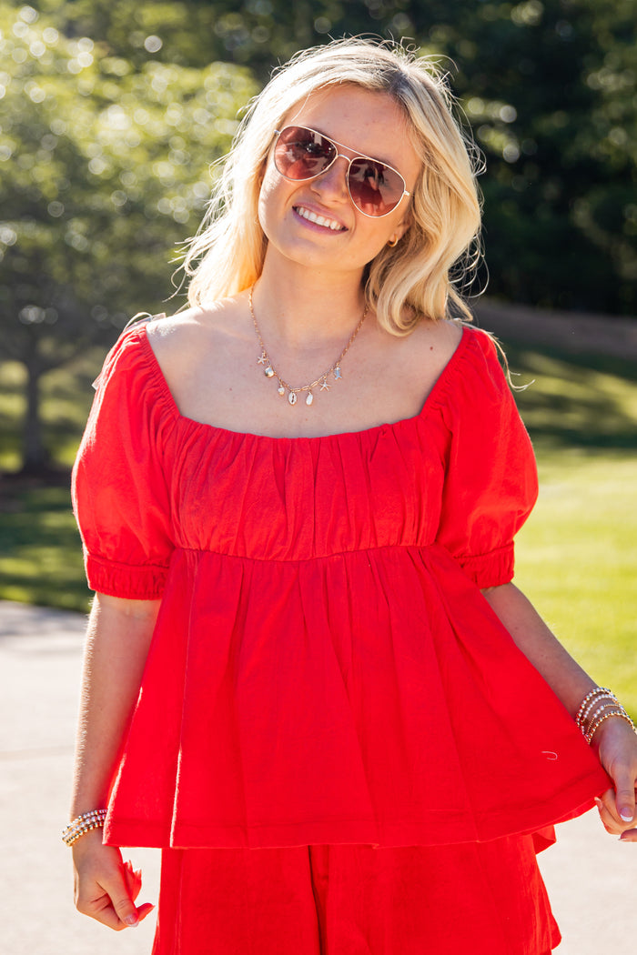 Woman wearing a red outfit with sunglasses outdoors