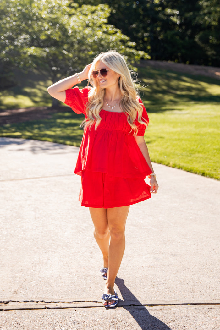 Woman in a red dress walking outdoors on a sunny day