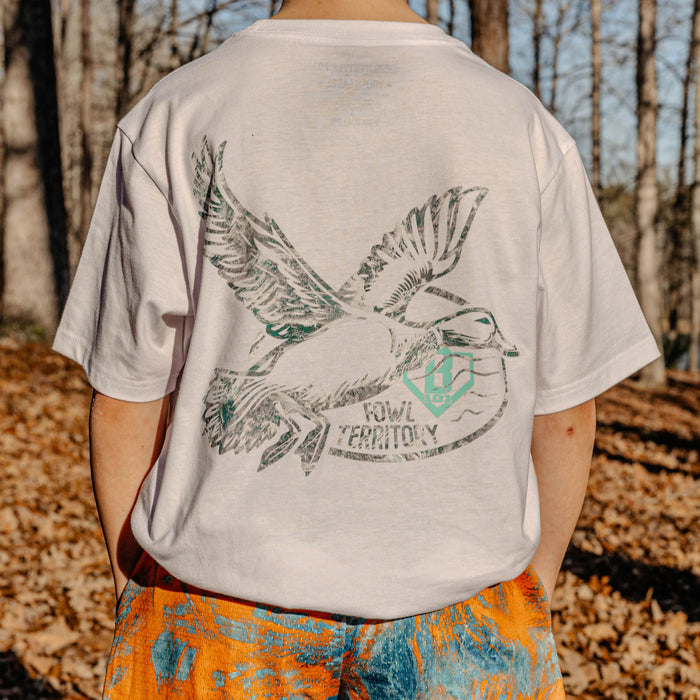 Person wearing a t-shirt with a bird graphic and 'Fowl Territory' text in a forest setting