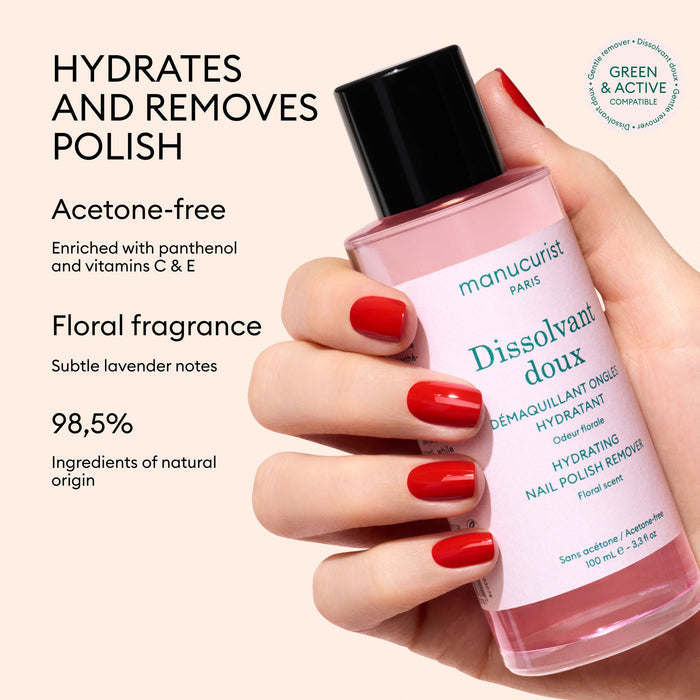 A hand with red-painted nails holds a pink bottle of Manucurist Gentle Remover. Text on the image highlights its acetone-free, hydrating floral formula, made with 98.5% natural ingredients.
