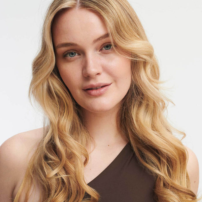 Light skinned woman with blond wavy hair on white background.