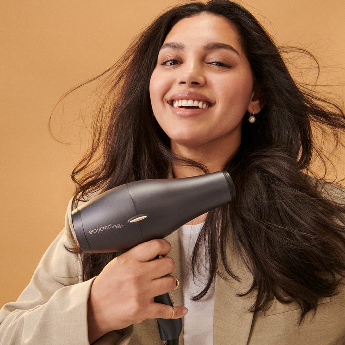 Woman with thick dark hair holding the GoldPro hair dryer.