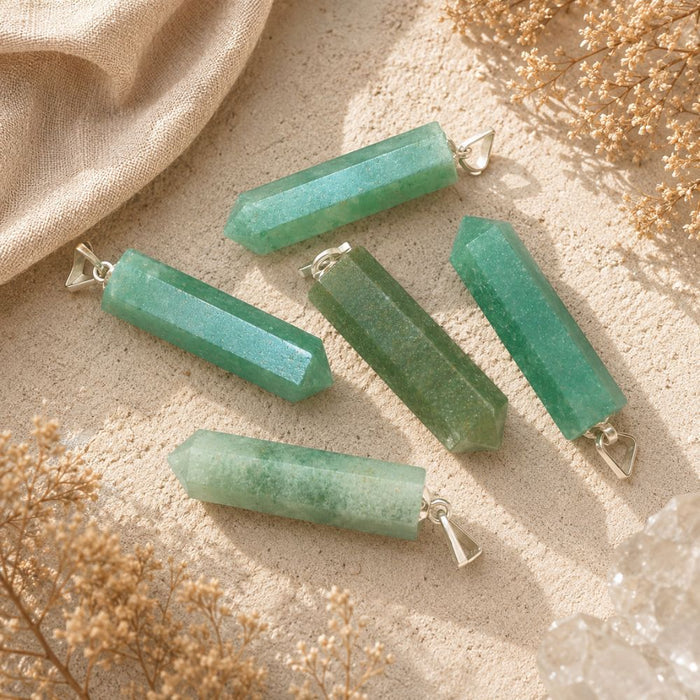 Green Aventurine point pendants displayed on a natural stone surface with soft linen and dried botanicals.