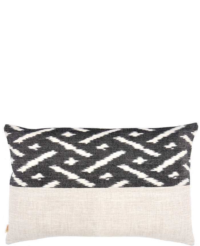 Rectangular throw pillow with black and white ikat patterned top half and natural linen bottom half