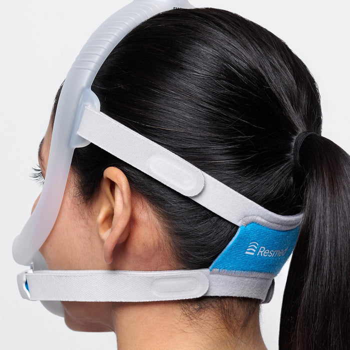 Person wearing a ResMed CPAP mask on a plain background