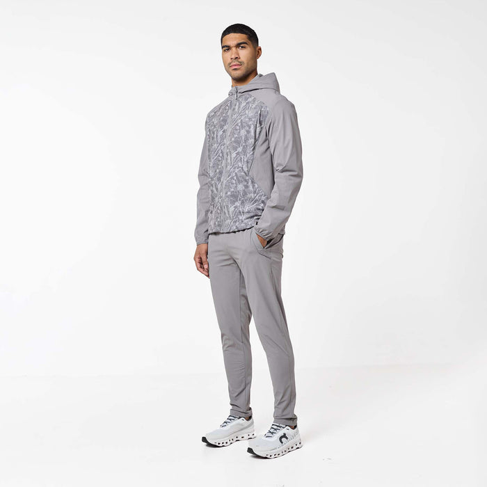 Model wearing the Ignite Tracksuit in Rock, highlighting the hooded jacket with printed front panels and matching tapered pants.