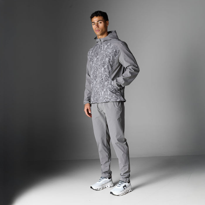Model wearing the Ignite Tracksuit in Rock, highlighting the hooded jacket with printed front panels and matching tapered pants.