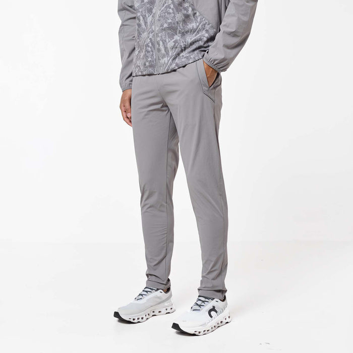 Close-up of the Ignite Tracksuit pants in Rock, showcasing the slim fit, concealed zip pocket and reflective piping detail.