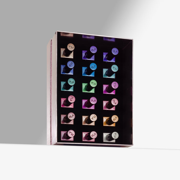 A rectangular black organizer tray holding 18 nail polishes in assorted metallic and pastel shades, photographed on a clean light gray studio background.