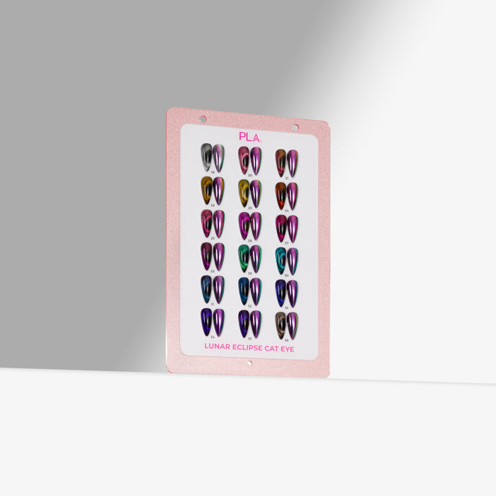 A pink display card showing multiple iridescent cat-eye false nail tips in different colors, labeled 'PLA' and 'Lunar Eclipse Cat Eye,' photographed against a light gray background.