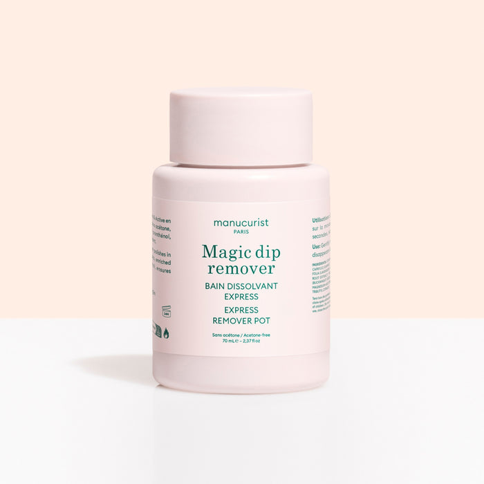 A light pink plastic container labeled Magic Dip Remover by Manucurist, this acetone-free express nail polish remover is perfect for travel touch-ups, shown against a pale beige and white background.