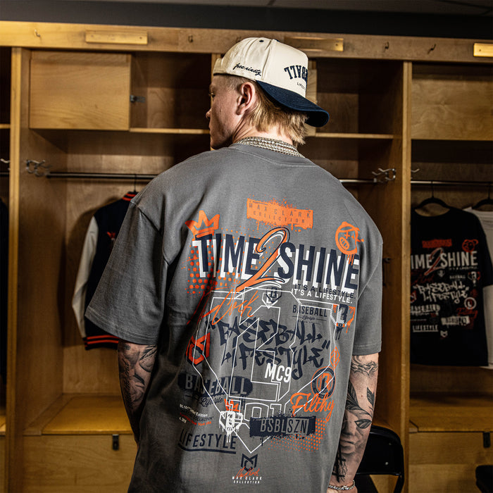 Person wearing a gray t-shirt with graphics and text in a locker room.