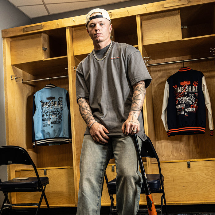 Person standing in a locker room with wooden lockers and jackets on display.