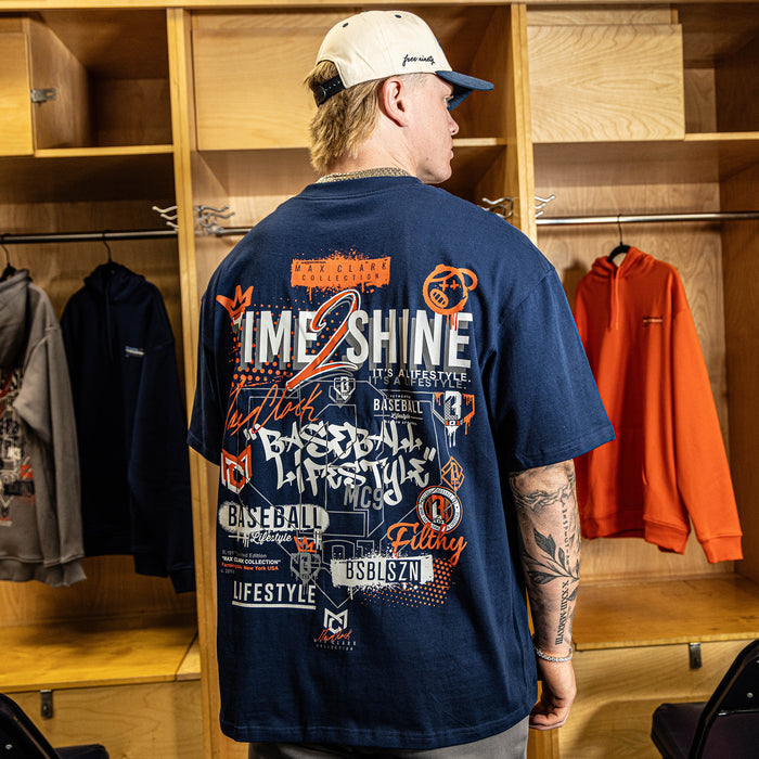 Person wearing a navy blue t-shirt with graphics and text in a locker room setting
