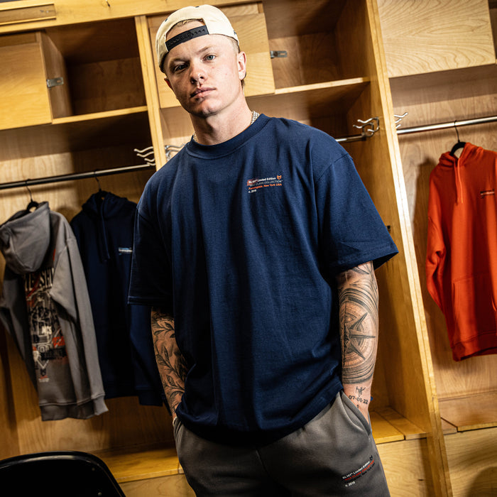 Man wearing a navy blue t-shirt with a logo in a locker room setting