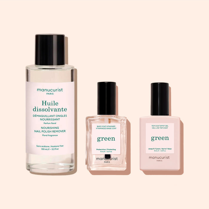 Three manicure products from Manucurist: a tall bottle of Nail Polish Removing Oil—nourishing, plant-based, and acetone-free—a square bottle of protective base coat, and another square bottle labeled "top coat" polish, all featuring black caps and set against a light beige background.